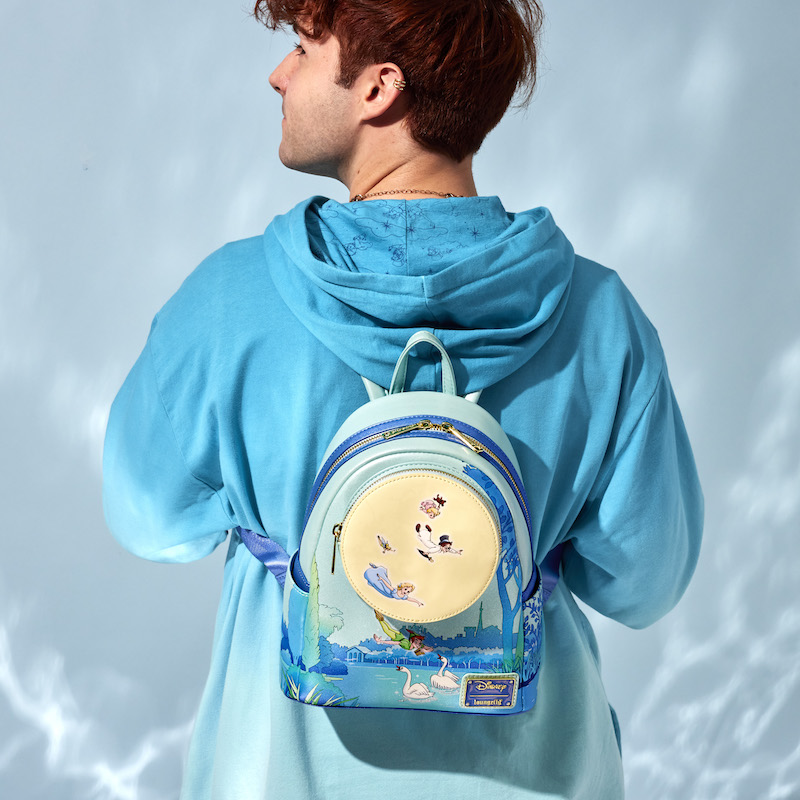 Image of man facing away from camera in a blue hoodie wearing the Loungefly Disney Peter Pan You Can Fly Glow Mini Backpack 